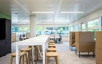 Bright workspace with high tables and stools, modern cubicles, and large windows in an office at Vasteland 42-110, Rotterdam Center. Ideal office space rental.