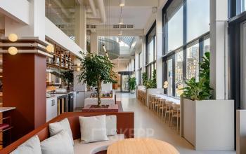 Bright, furnished office space with large windows and modern furnishings, located at Vasteland 42-110, Rotterdam Center. Ideal for office space rental with inviting seating and a chic atmosphere.