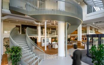 Modern office space in Vasteland 42-110, Rotterdam Center featuring a spiral staircase, open floor plan, and natural light, ideal for office space rental.