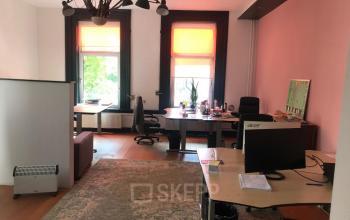 Office at Schiekade 105, Rotterdam Center with modern furniture, ample natural light from large windows, and three workstations equipped with desks and chairs.