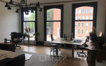 Bright office space rental at Schiekade 105 in Rotterdam Center featuring large windows, desks with chairs, and modern lighting.