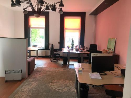 Office at Schiekade 105, Rotterdam Center with modern furniture, ample natural light from large windows, and three workstations equipped with desks and chairs.