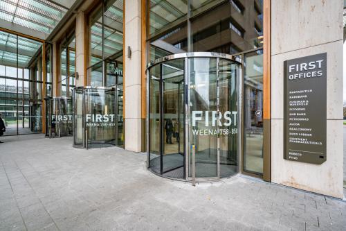 Exterior view of office space rental entrance at Weena 788, Rotterdam Center, featuring modern revolving glass doors with signage for First Offices.