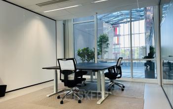 Bright office space at Kruisplein 480, Rotterdam Center with modern furnishings, glass walls, and indoor plants, perfect for business meetings. Ideal for office space rental.