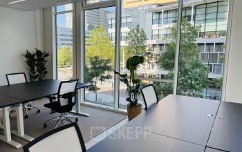 Bright and airy office space rental at Kruisplein 480, Rotterdam Center, featuring large windows and modern furniture, creating an ideal workspace environment.