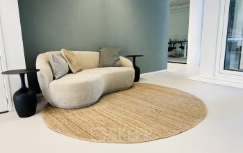 Cozy lounge area in Kruisplein 480 with a modern sofa, side tables, and a circular rug, ideal for office space rental in Rotterdam Center.