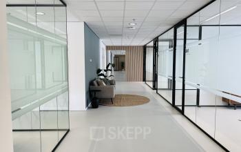 Modern office interior at Kruisplein 480, Rotterdam Center featuring glass-walled corridors and a seating area. Ideal for office space rental with sleek design and ample natural light.