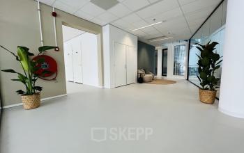 Modern corridor at Kruisplein 480, Rotterdam Center, featuring minimalistic design with glass walls and potted plants, ideal for office space rental.