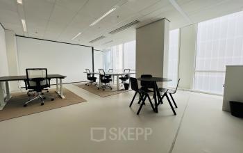 Spacious interior of an office at Kruisplein 480, Rotterdam Center, featuring minimalist workspaces with modern desks and chairs, ideal for office space rental.