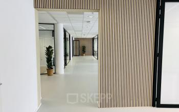 Spacious and modern hallway with stylish wooden paneling and potted plants at Kruisplein 480, Rotterdam Center, perfect for your next office space rental.