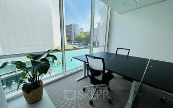 Bright office space at Kruisplein 480, Rotterdam Center, featuring a modern black desk, ergonomic chair, and large windows offering city views. Ideal for businesses seeking a workspace rental with natural light.