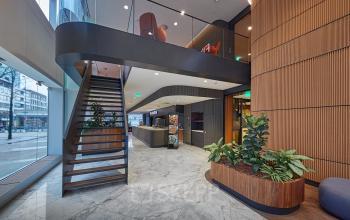 Modern office interior at Blaak 555, Rotterdam Center featuring a sleek staircase, natural lighting, and stylish planter boxes, ideal for office space rental.