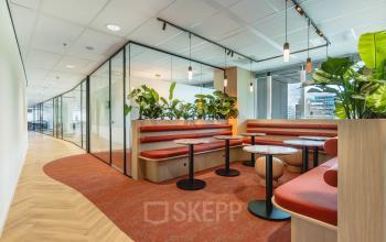 Modern furnished office space at Blaak 555, Rotterdam Center, featuring stylish seating areas and greenery. Ideal office space rental opportunity.