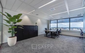 Bright, furnished office space at Blaak 555, Rotterdam Center, featuring large windows, modern furniture, and a city view. Ideal for office space rental.