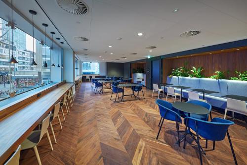 Spacious office in Blaak 555, Rotterdam Center, featuring modern workspaces with blue seating, wood flooring, and large windows ideal for office space rental.