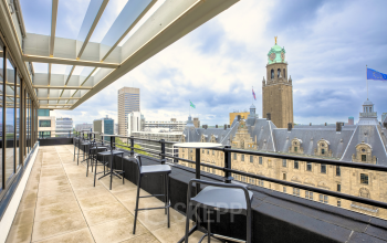 A scenic balcony view from an office to rent at Coolsingel 65, showcasing Rotterdam's skyline with tables and chairs arranged for a pleasant break or informal meeting.