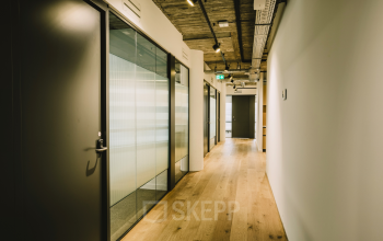 View down a modern office hallway with wood flooring and glass doors at Coolsingel 65, ideal for office space rental.