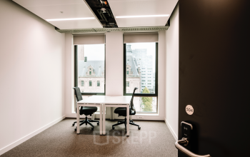 A modern furnished office at Coolsingel 65, Rotterdam Center, featuring two desks and large windows offering a city view, ideal for office space rental.