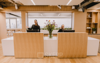 Modern office reception area at Coolsingel 65, Rotterdam Center, with two people at the desk, ideal for office space rental inquiries.