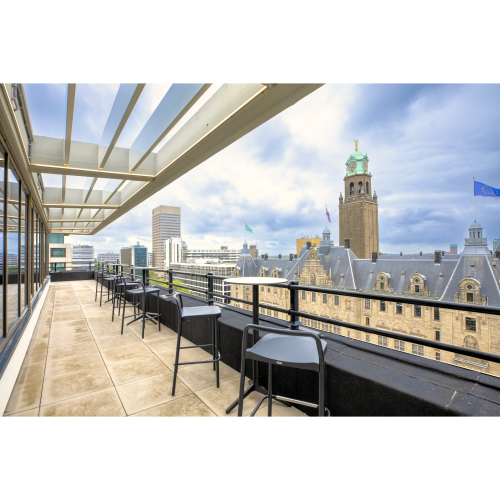 A scenic balcony view from an office to rent at Coolsingel 65, showcasing Rotterdam's skyline with tables and chairs arranged for a pleasant break or informal meeting.