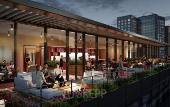 People relax and socialize in a spacious rooftop lounge area of a modern office building at Hoogstraat 185, Rotterdam Center, ideal for office space rental.