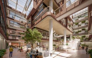 Spacious open-floorplan office with contemporary design at Hoogstraat 185, Rotterdam Center. Features seating areas under a glass roof with natural light. Rent office space and enjoy a vibrant work environment.