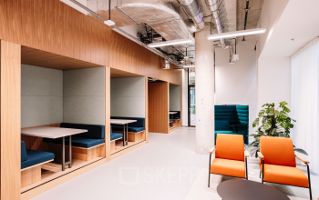 Modern office space in Rotterdam Center with stylish wooden booths and colorful seating, perfect for collaboration or meetings. Ideal for office space rental in a vibrant location.