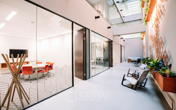 Modern office space for rent in Rotterdam Center with glass-walled conference rooms and stylish seating area, located at Hoogstraat 185.
