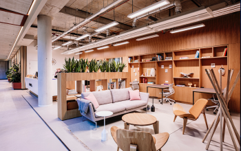 Modern furnished office space for rent at Hoogstraat 185, Rotterdam Center, featuring stylish seating and workspaces with plants and shelves for a comfortable office space rental experience.