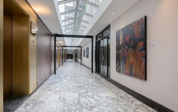 Modern office corridor with marble flooring and colorful artwork on the walls in Weena 87, Rotterdam Center, ideal for professional office space rental.