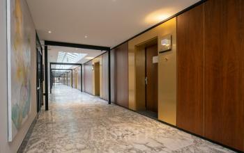 Spacious corridor at Weena 87, Rotterdam Center, featuring marble floors and wooden wall accents, leading to various office spaces available for rent.