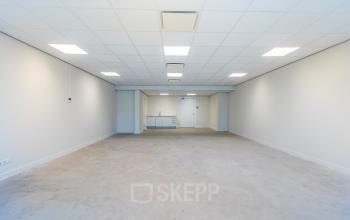 Spacious unfurnished office space available for rent at Weena 87, Rotterdam Center, featuring neutral walls, a minimalist design, and bright fluorescent lighting ideal for customization and setup.