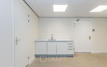 Minimal interior of Weena 87 office in Rotterdam Center, featuring a small kitchenette with a sink and light fixtures. Ideal for office space rental.