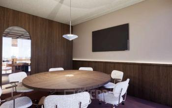 Modern office space in Rotterdam Center featuring a round wooden table and six stylish chairs, ideal for meetings or collaborative work sessions. Perfect for those seeking office space rental at Coolsingel 139.