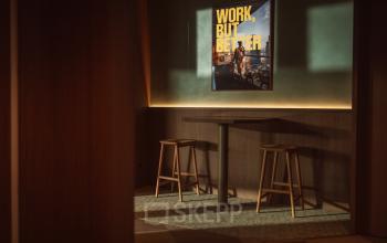 Cozy corner with stools and a high table beneath a motivational poster in an office to rent at Coolsingel 139, Rotterdam Center.