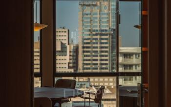 Interior view of a furnished office space with large windows overlooking Rotterdam Center. Ideal for office space rental with a collaborative setup.