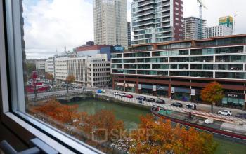View from an office to rent at Wijnhaven 76 in Rotterdam Center, overlooking modern buildings and a canal.