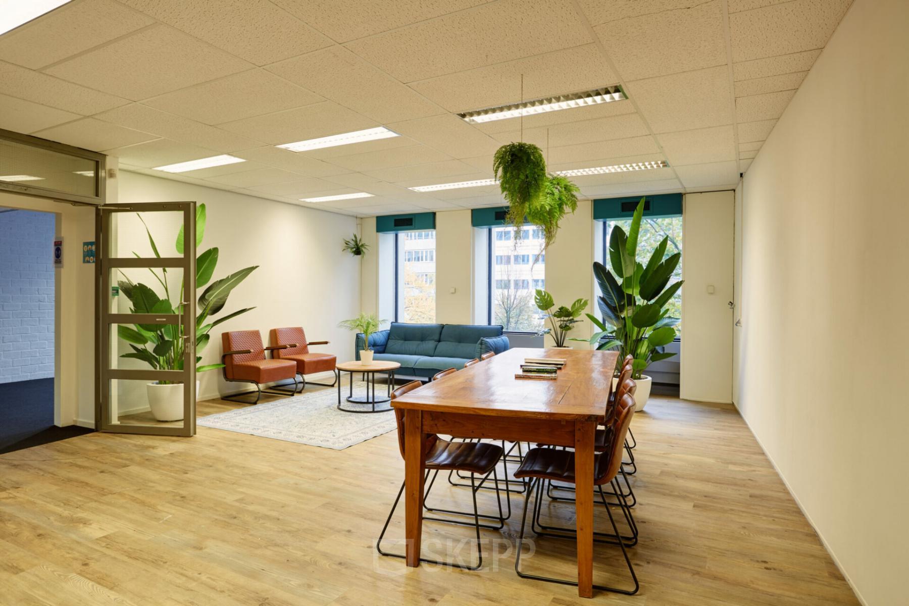 Modern office space rental at Westblaak 92, in Rotterdam Center, featuring a cozy lounge area with plush seating and lush green plants.
