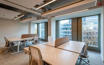 Bright modern office space at Stadhuisplein 9-23 in Rotterdam Center featuring large windows and contemporary furniture.