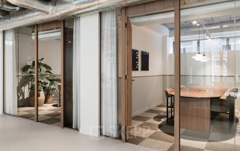 Modern office to rent at Stadhuisplein 9-23, Rotterdam Center, featuring glass-walled workspaces and stylish furnishings, ideal for productive meetings and collaborations.