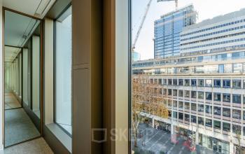 View from the interior of an office space in Stadhuisplein 9-23, Rotterdam Center, overlooking urban buildings and a construction site, ideal for office space rental.