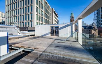 Spacious outdoor deck at Stadhuisplein 9-23, Rotterdam Center, offering potential for an office space rental with views of surrounding buildings.