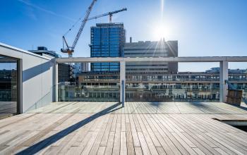 Bright rooftop area for office space rental at Stadhuisplein 9-23, Rotterdam Center with views of city buildings and construction cranes.