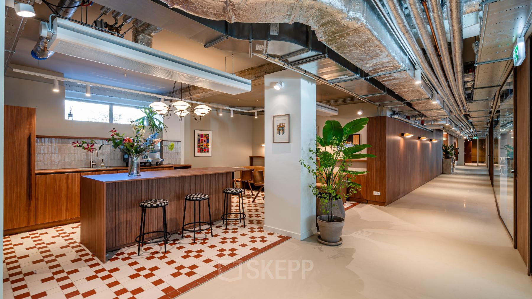 Modern office interior in Rotterdam Center with a stylish open floor plan featuring decorative plants, a bar-height table, and stools for collaborative work. Ideal office space rental with flexible options.