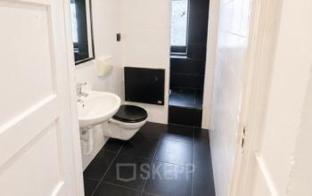 Office restroom at Mauritsweg 33 A01 in Rotterdam Center, featuring modern fixtures and sleek black and white tiling, available for office space rental.
