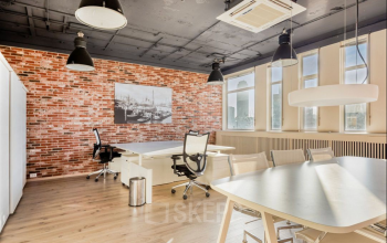 Spacious office space at Veerhaven 7, Rotterdam Center with modern furnishings, large windows, and a stylish brick accent wall. Ideal for office space rental.