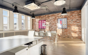 Spacious office space at Veerhaven 7, Rotterdam Center, featuring exposed brick walls, ample natural light, and modern furnishings. Ideal for office space rental with a mix of desks and a meeting area.