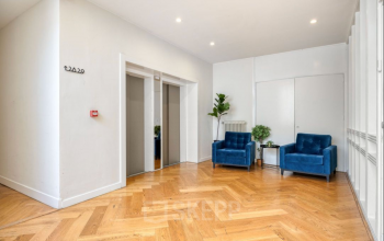 Modern office entrance with wooden flooring and two blue armchairs at Veerhaven 7, Rotterdam Center, ideal for office space rental.