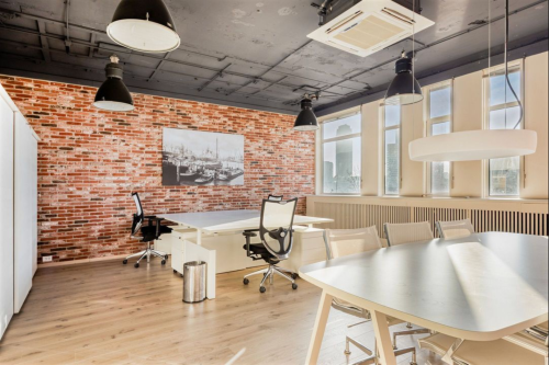 Spacious office space at Veerhaven 7, Rotterdam Center with modern furnishings, large windows, and a stylish brick accent wall. Ideal for office space rental.