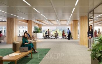 Modern office space at Coolsingel 75, Rotterdam Center, with professionals engaging in discussions and laptop work. Bright and furnished for office space rental.